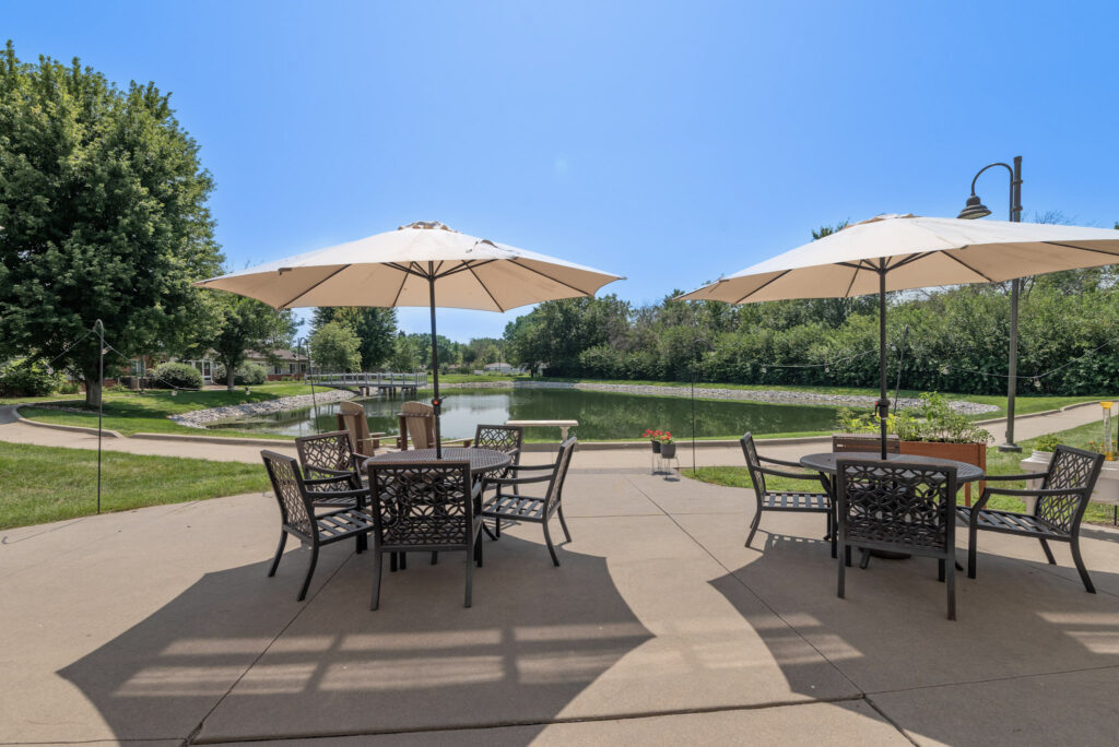 patio with two tables and umbrellas overlooking a pond